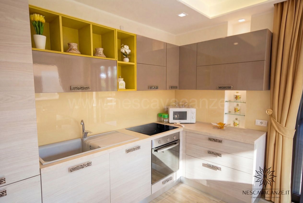 Casa Giglio - cucina angolare beige lucida con pensili gialli, piano cottura a induzione, forno e microonde