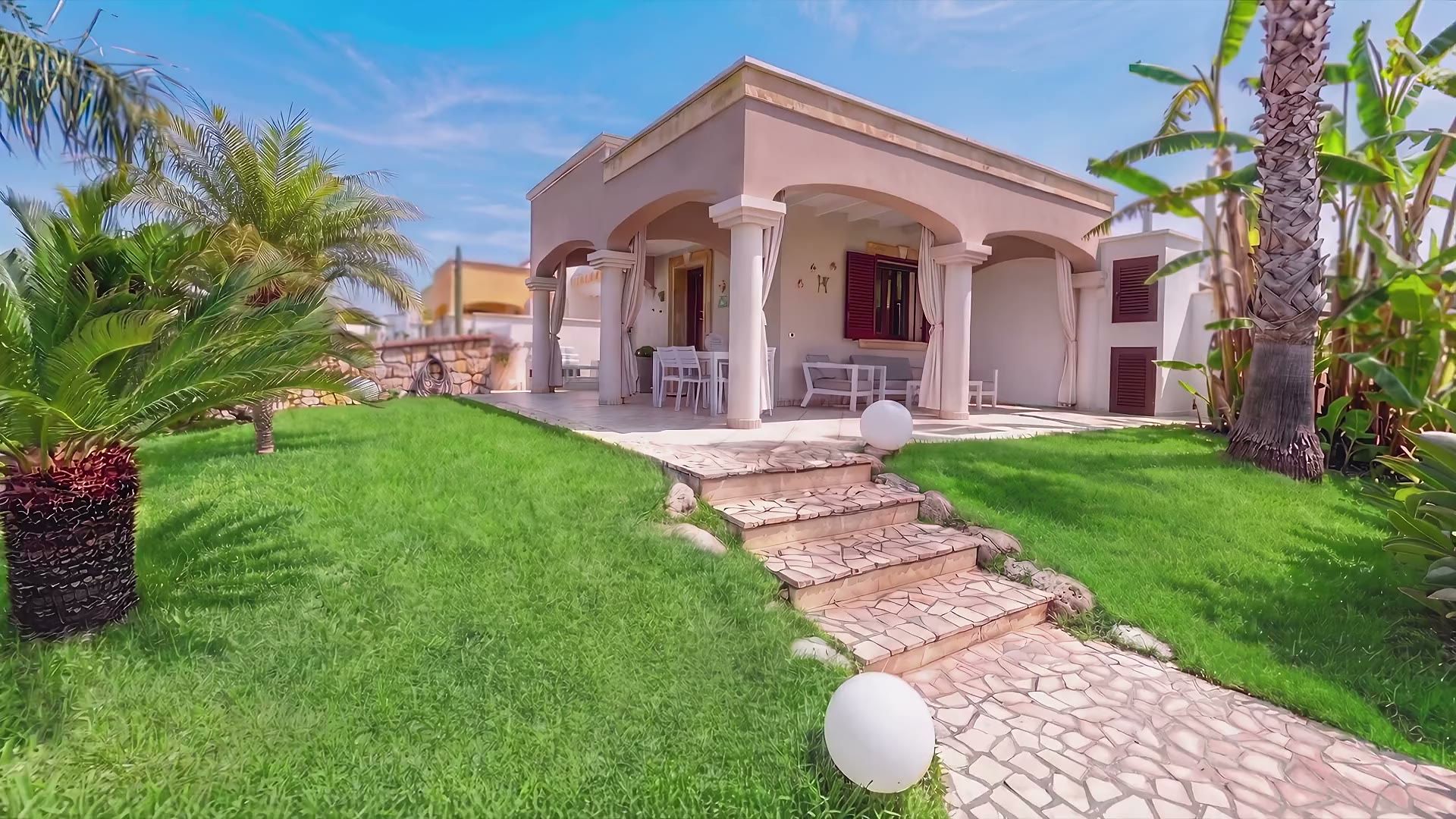 La facciata di Casa Pescoluse 8 con il porticato ad archi e i gradini in pietra che salgono dal prato