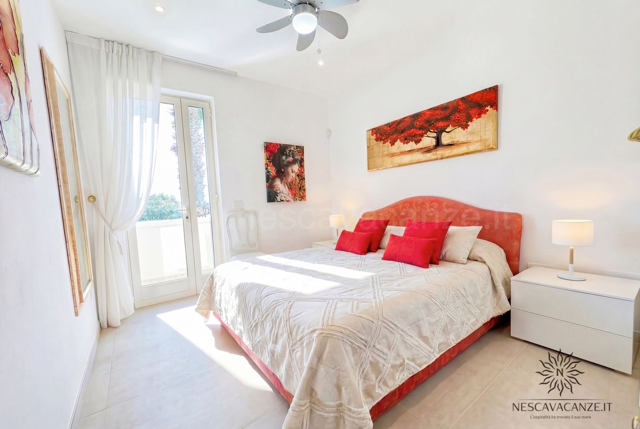 Casa Pescoluse 1 - camera matrimoniale con testiera rossa, cuscini rossi e quadro con albero