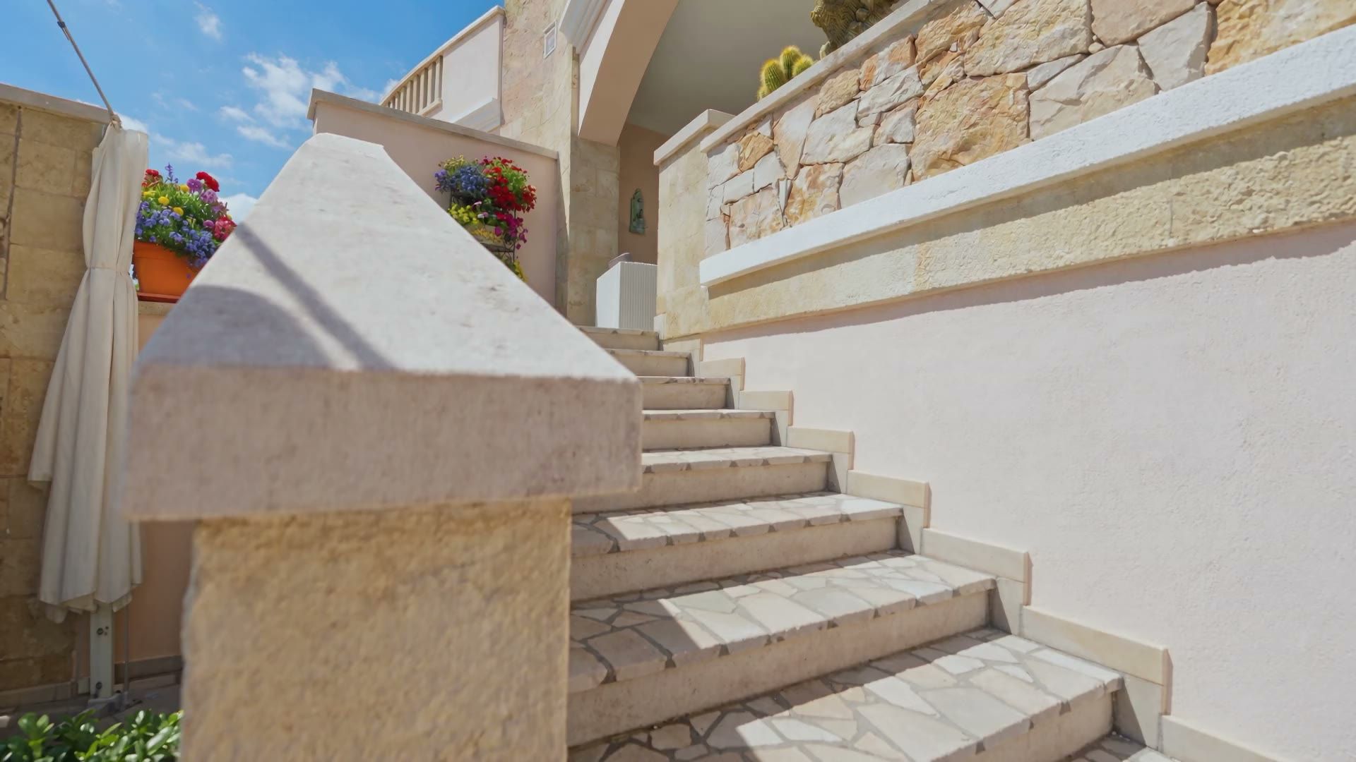 La scala esterna in pietra di Casa Pescoluse 5 che sale dal cortile alla veranda, con le fioriere e i cactus