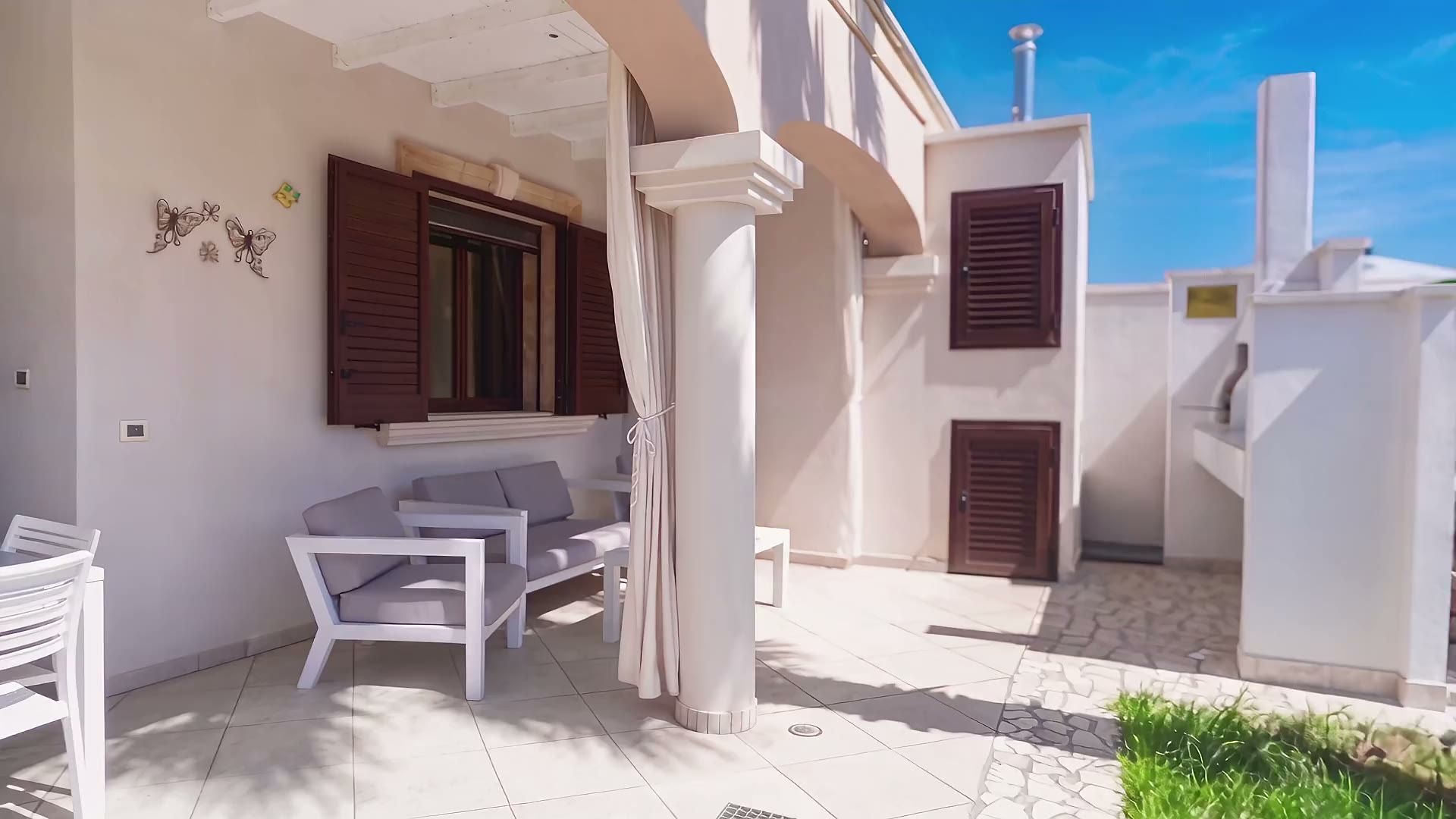 La veranda coperta di Casa Pescoluse 8 con i divanetti, il tavolo da pranzo e il barbecue in muratura