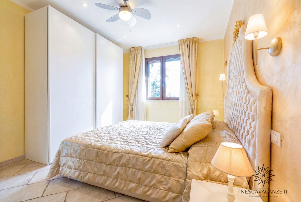 Casa Pescoluse 8 - Camera da letto con armadio bianco, letto matrimoniale dorato e finestra luminosa