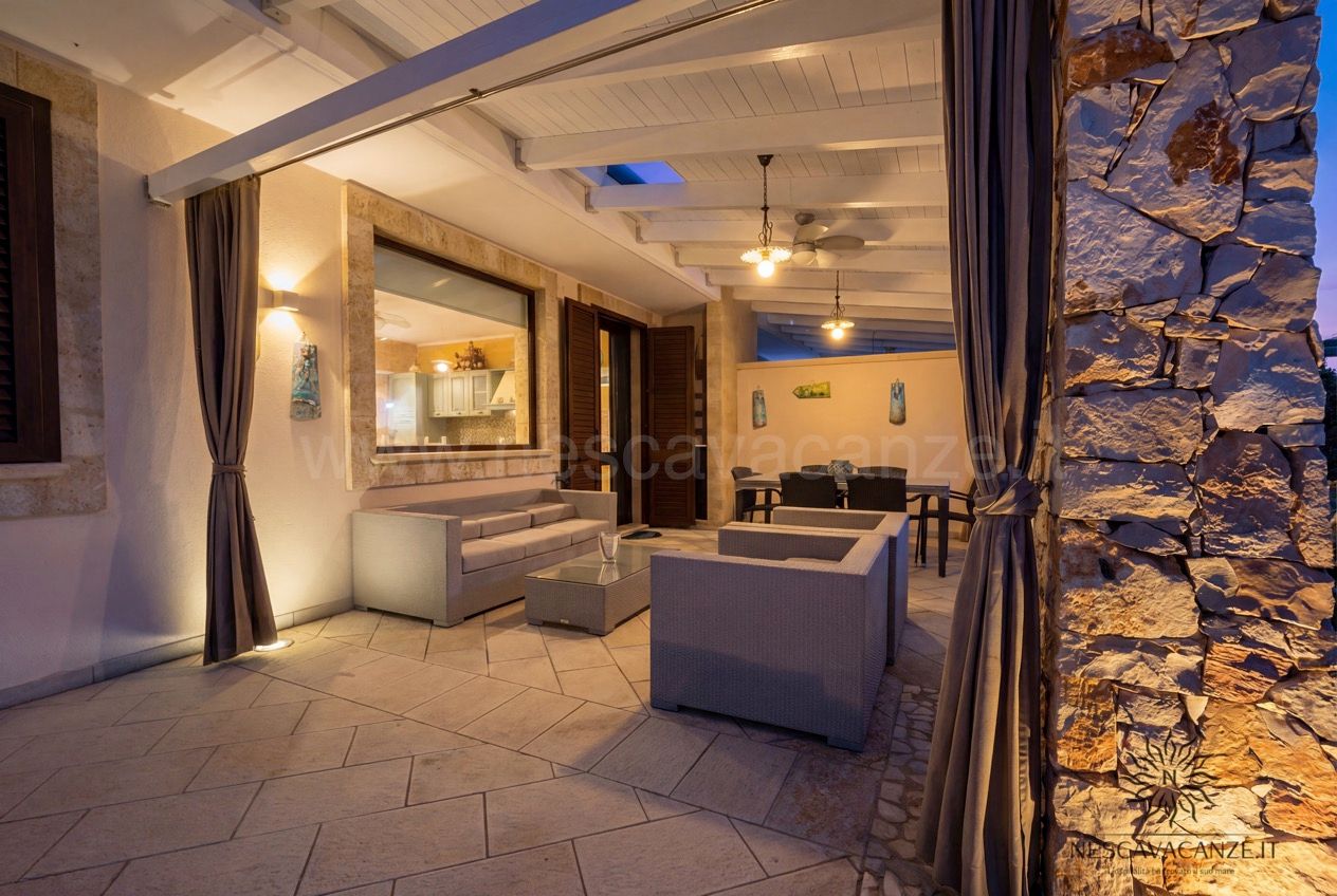 Casa Pescoluse 7 - salotto esterno coperto illuminato di sera con divani grigi