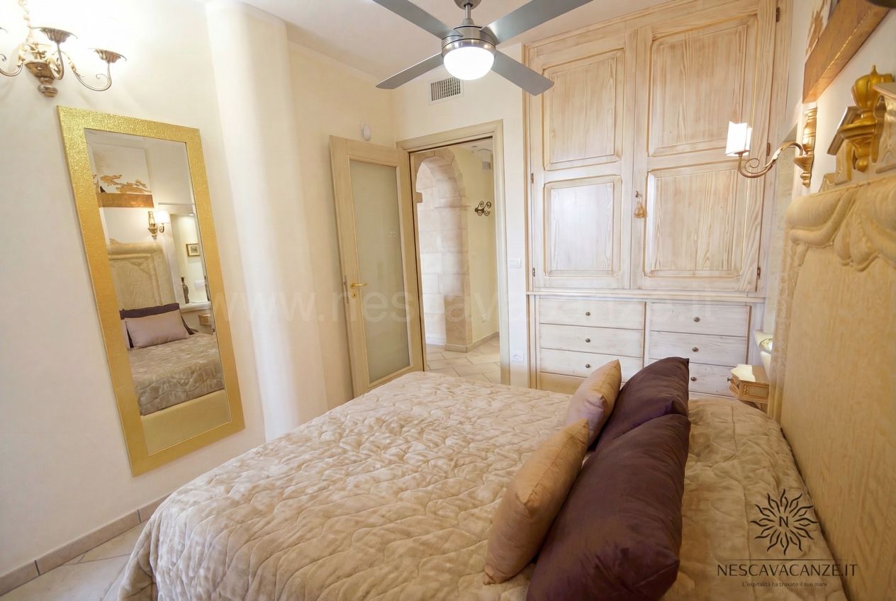 Casa Pescoluse 6 - camera matrimoniale con specchiera dorata, armadio in legno chiaro e ventilatore a soffitto