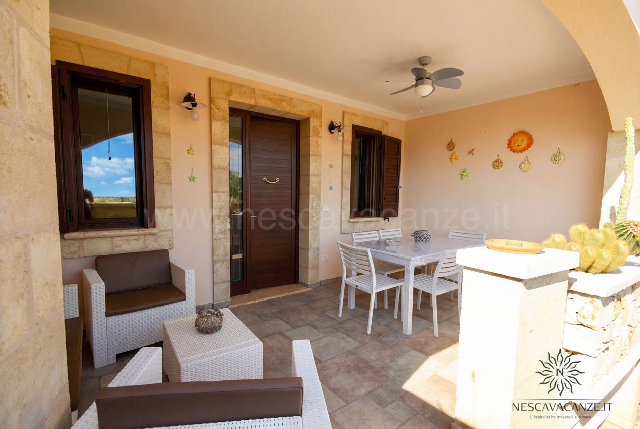 Casa Pescoluse 5 - portico coperto con porta d'ingresso, tavolo da pranzo e poltrone in rattan