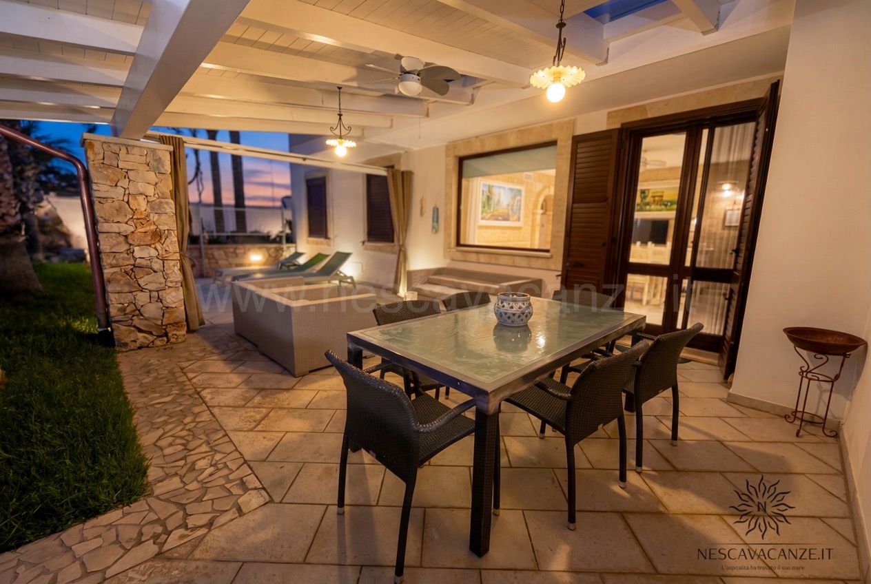 Casa Pescoluse 7 - terrazza coperta con tavolo da pranzo al tramonto con vista mare