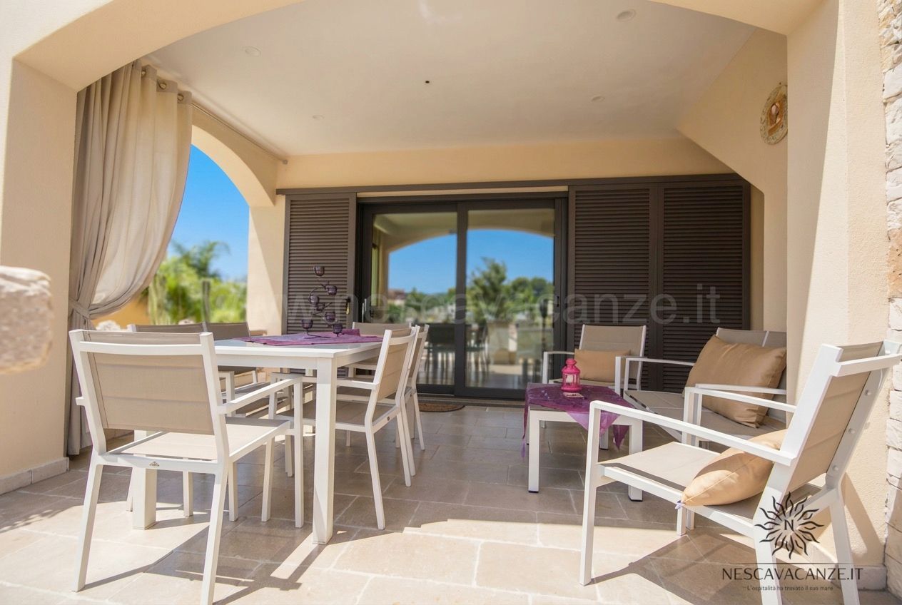 Casa Giglio - veranda coperta con tavolo bianco, poltrone, tende e vista sul giardino