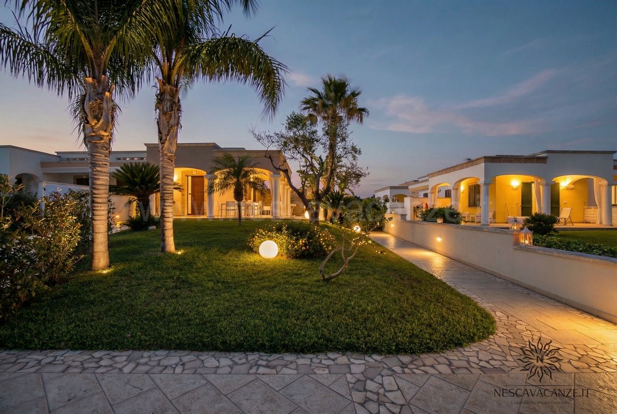 Casa Pescoluse 8 - Giardino al crepuscolo con palme e villa illuminate e vialetto in pietra