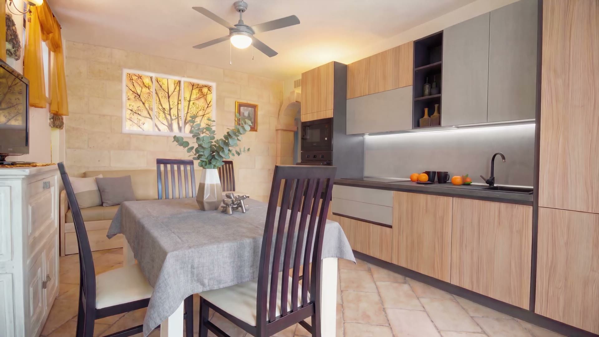 La cucina di Casa Pescoluse 6 in legno chiaro e grigio, con il quadro degli alberi sulla parete in pietra e l'arco che porta alla zona notte