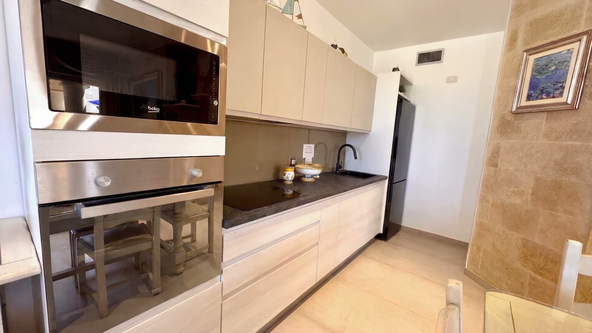 L’angolo cottura di Casa Pescoluse 1 con il forno, il microonde, il piano a induzione e il frigorifero