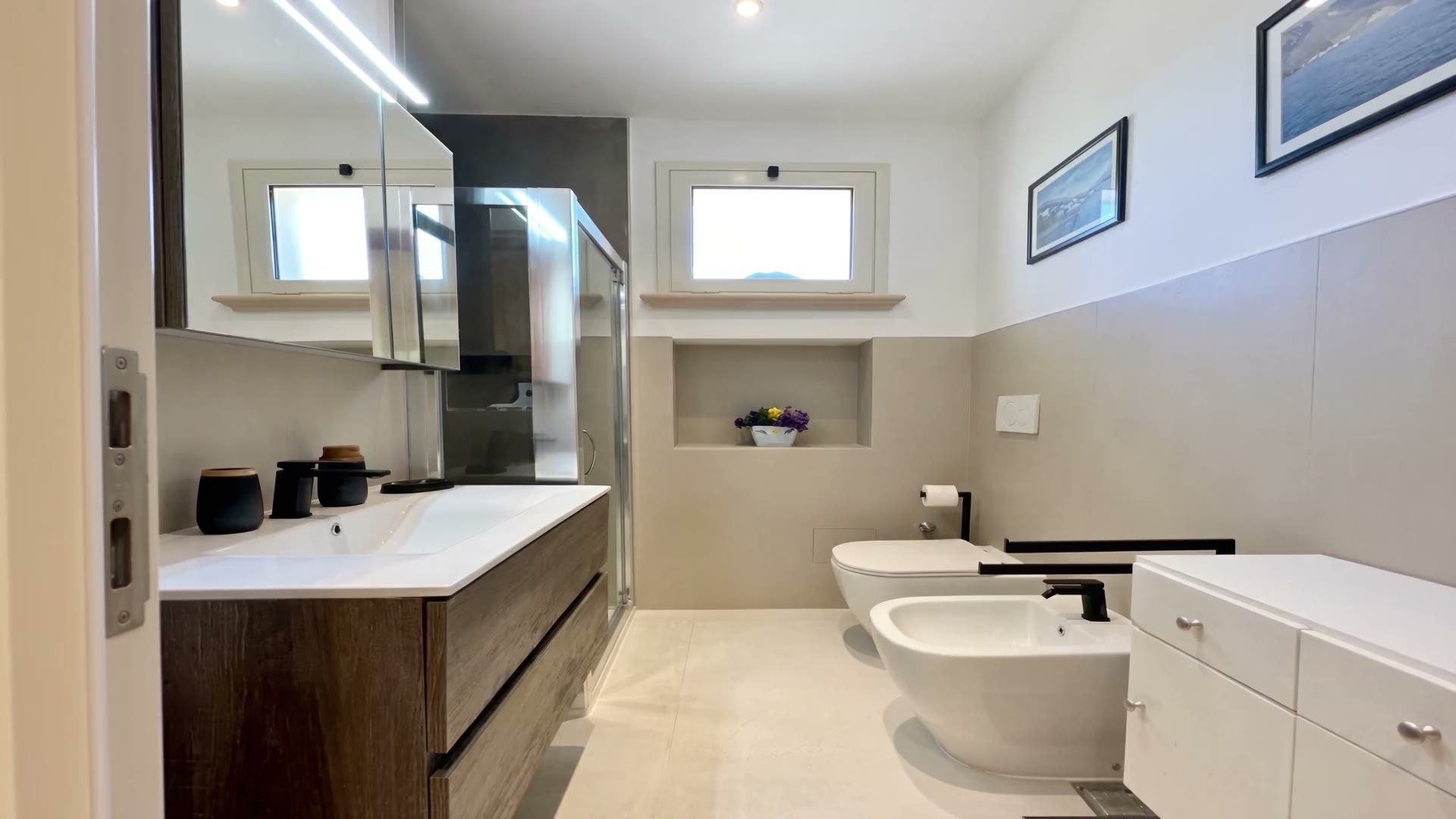 Il bagno di Casa Pescoluse 3 con il mobile in rovere, la specchiera e il box doccia in vetro