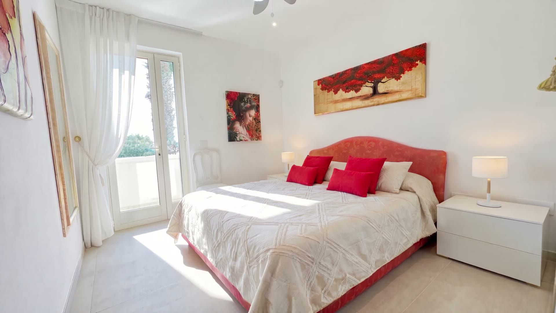 La camera matrimoniale di Casa Pescoluse 1 con la testiera rossa, l’armadio bianco e il quadro con l’albero