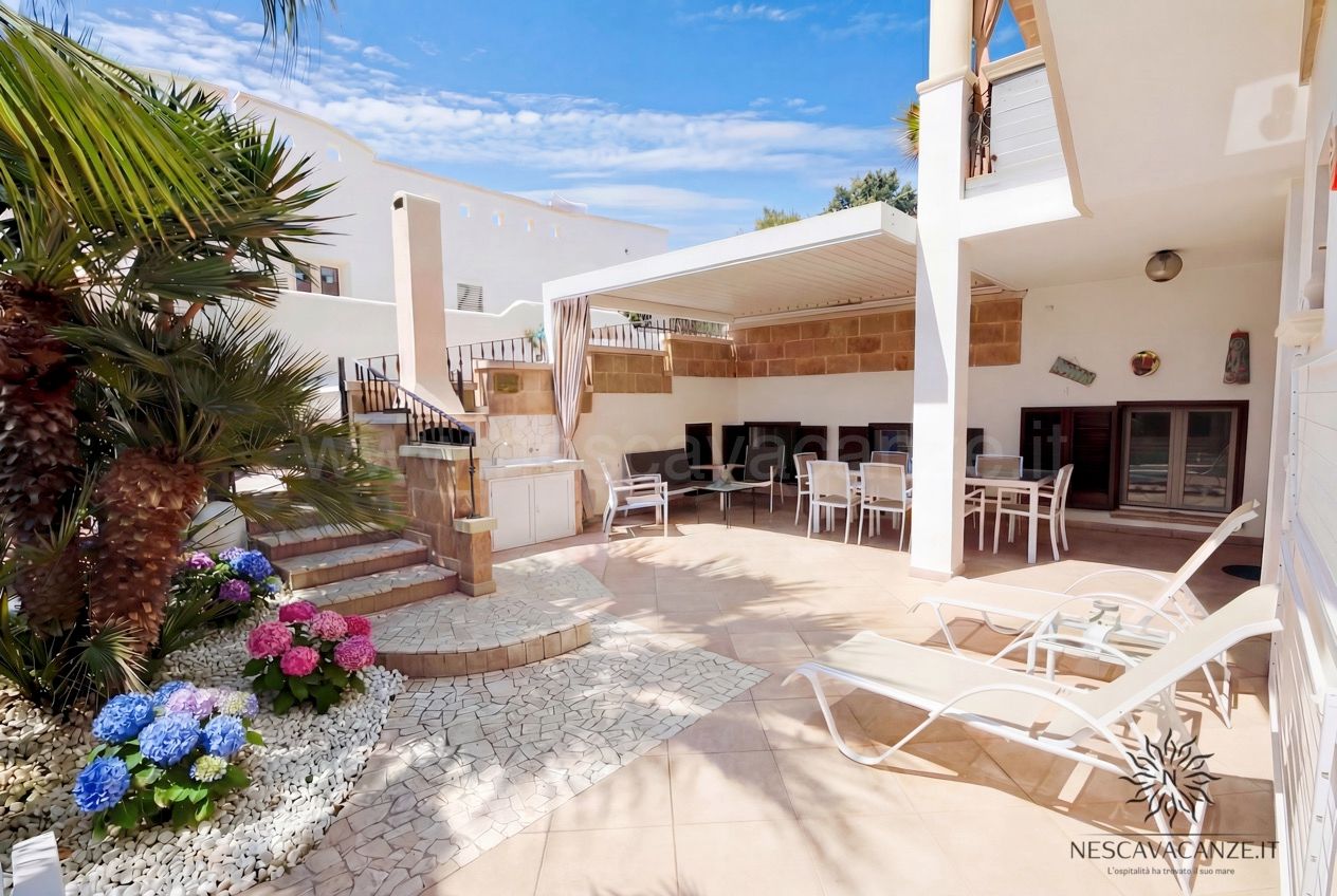 Casa Pescoluse 2 - patio con pergola bioclimatica, tavolo, lettini e aiuola di ortensie