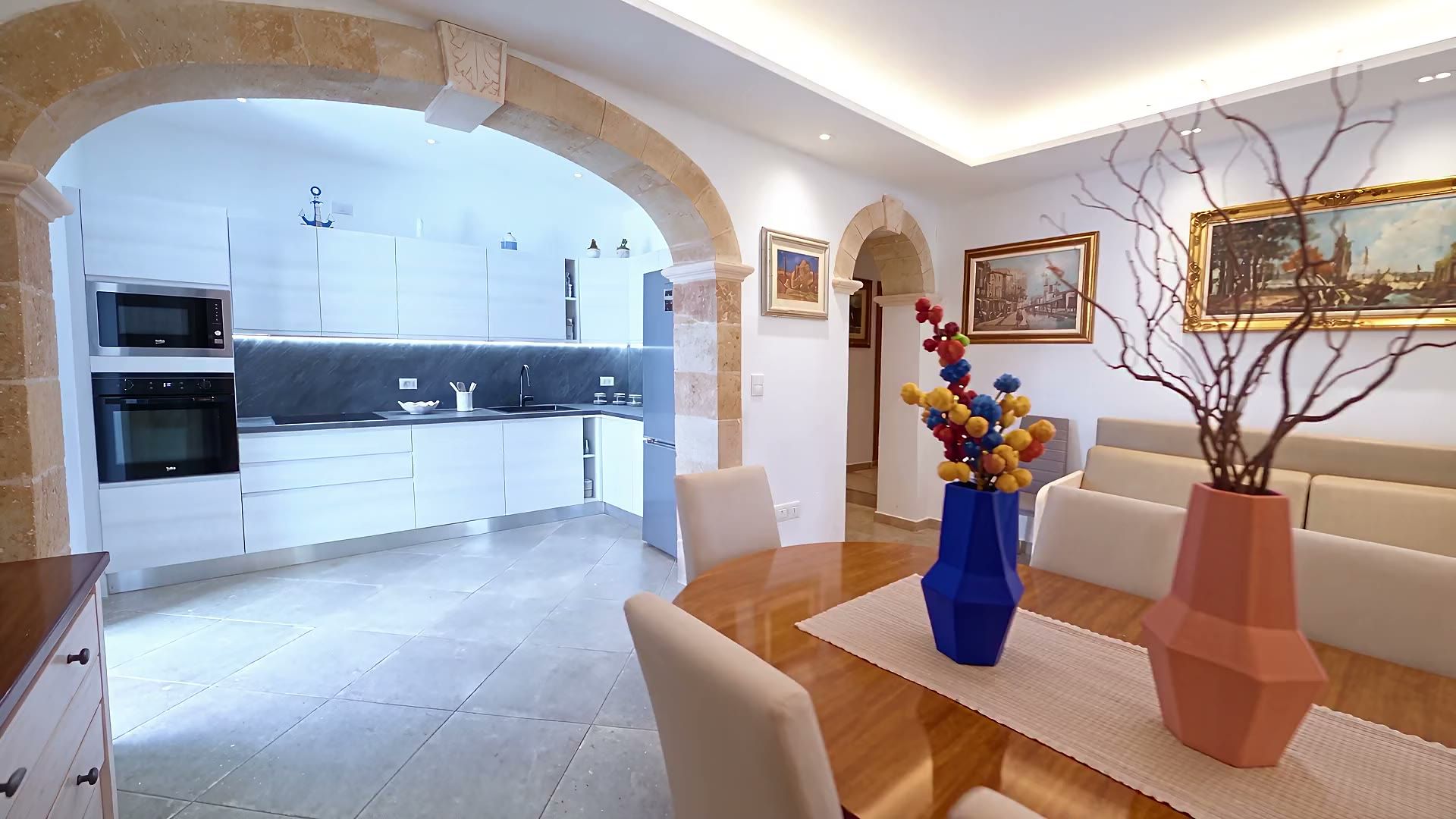 La cucina di Casa Pescoluse 9 con le ante chiare, lo schienale in marmo scuro, i due forni da incasso e il frigorifero