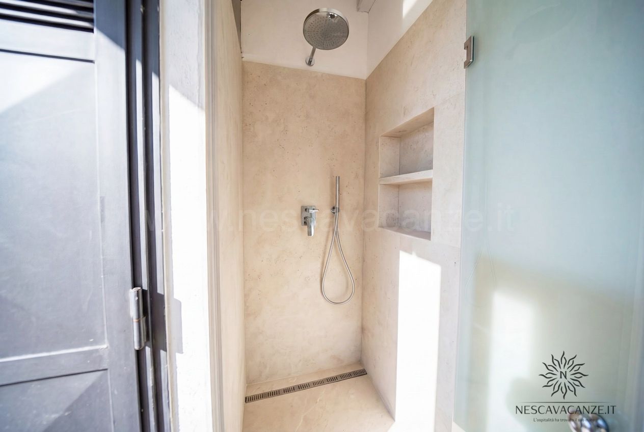 Casa Sabbia Oro - doccia walk-in in microcemento beige con soffione a pioggia e nicchia portaoggetti