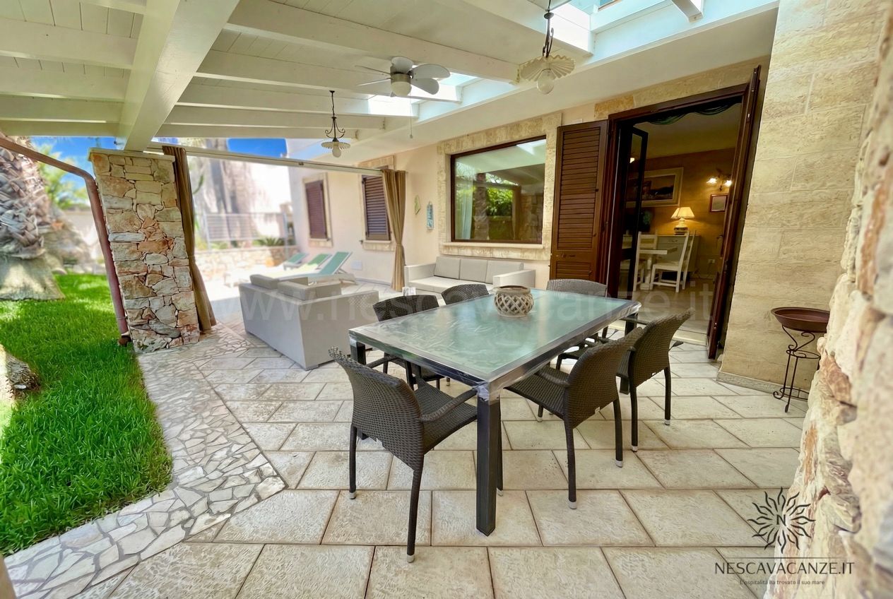 Casa Pescoluse 7 - terrazza coperta con tavolo da pranzo e divani, vista sul giardino