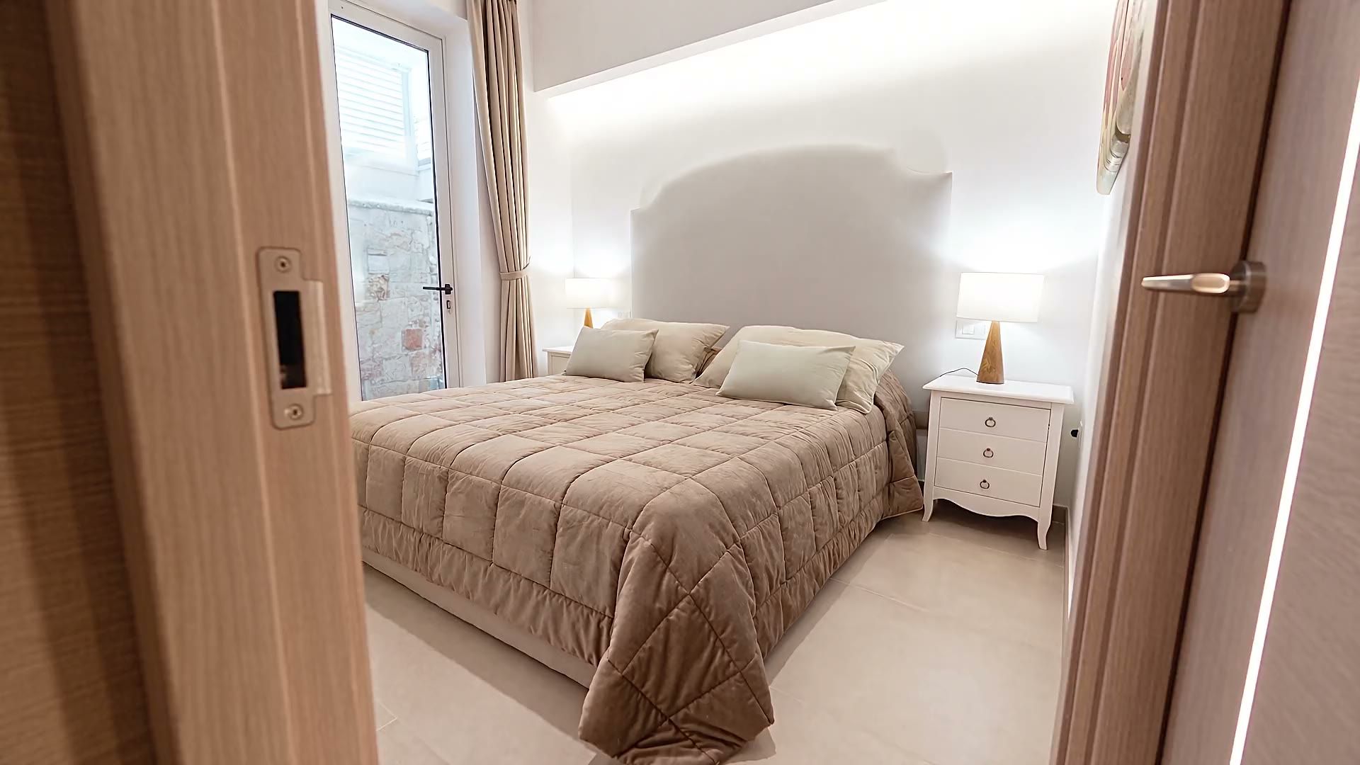 La prima camera matrimoniale di Casa Pescoluse 2 con la testiera imbottita, le nicchie illuminate e i quadri di papaveri