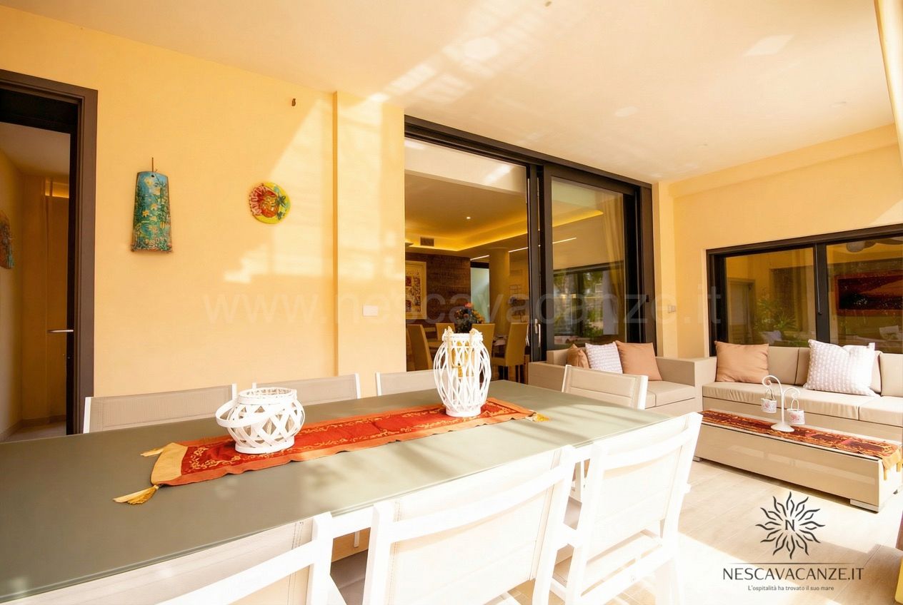 Casa Salento - veranda con tavolo, divano e tende affacciata sul soggiorno illuminato