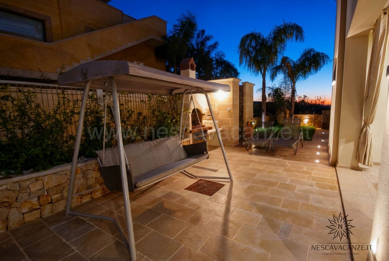 Casa Salento - terrazza al tramonto con dondolo, barbecue e lettini illuminati e palme