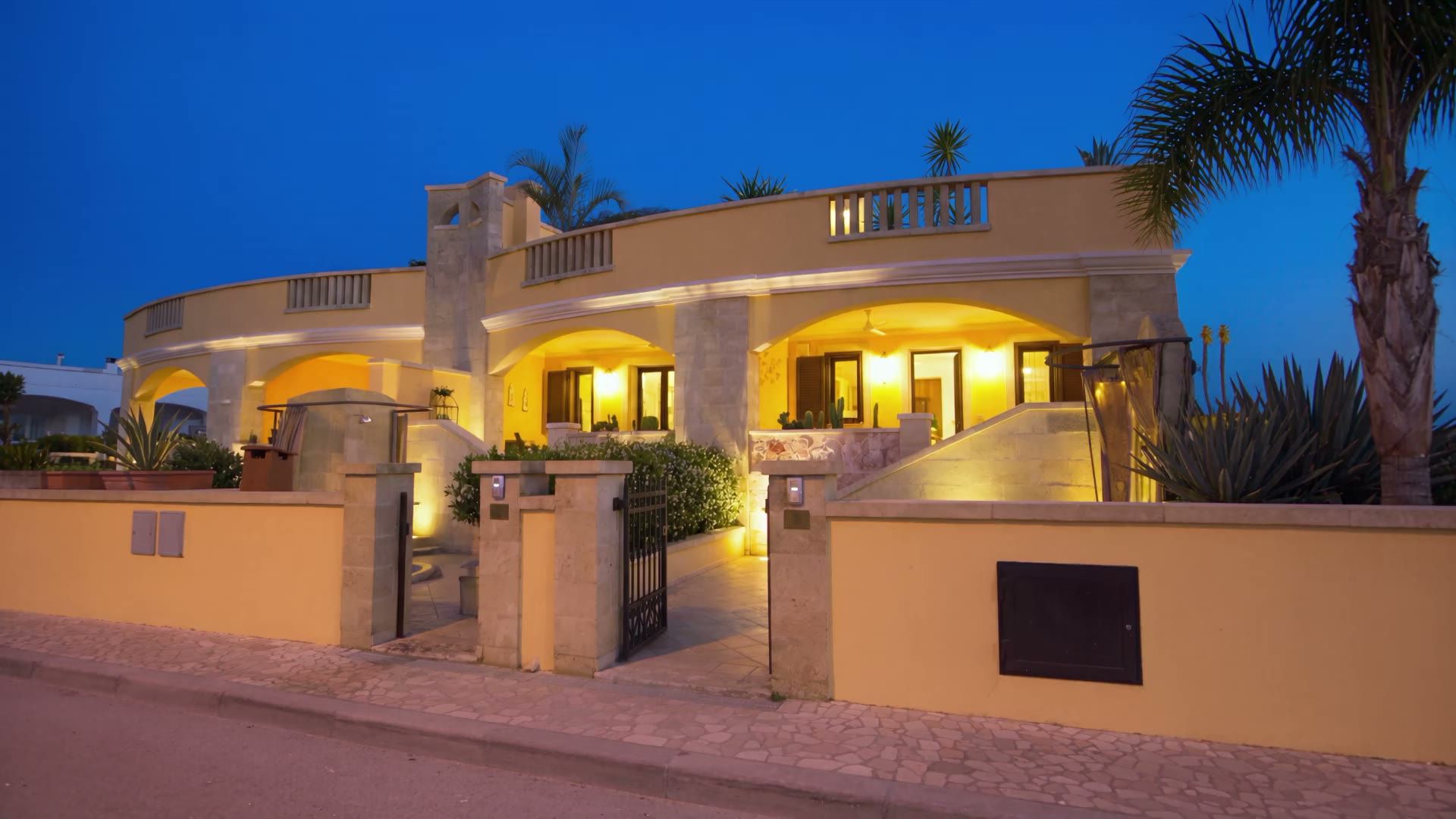 Casa Pescoluse 5 illuminata al crepuscolo vista dalla strada, con gli archi accesi e il cielo blu notte