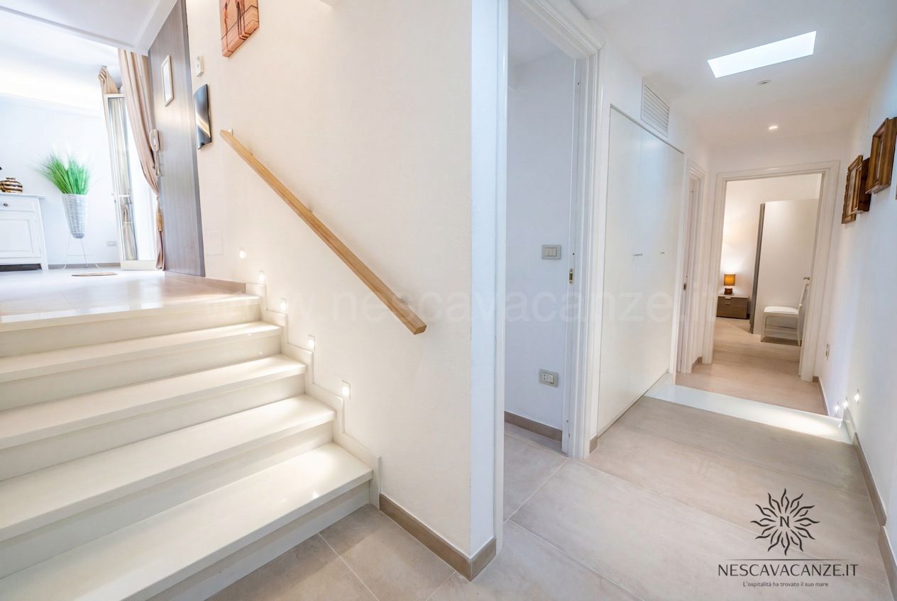 Casa Pescoluse 2 - scala interna chiara con corrimano in legno e corridoio verso le camere