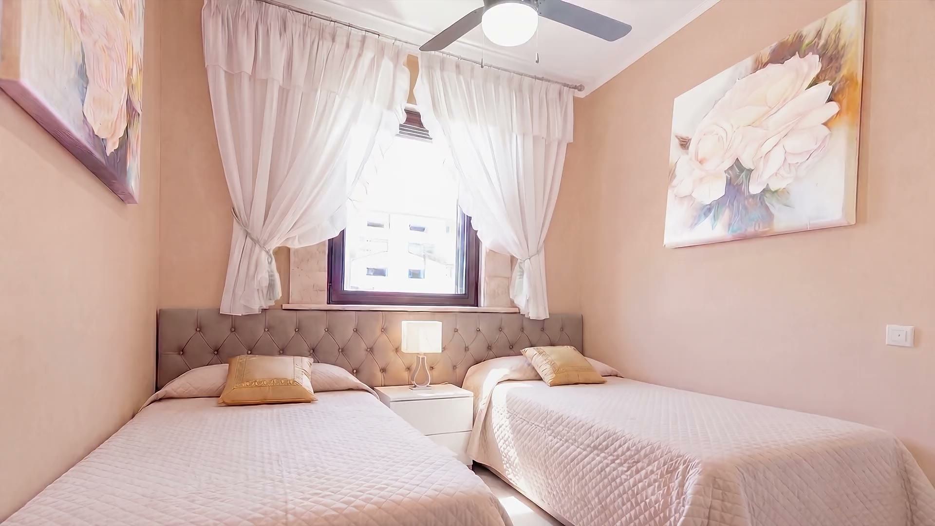 La camera con i due letti singoli di Casa Pescoluse 4, la finestra con le tende bianche e il quadro con le rose
