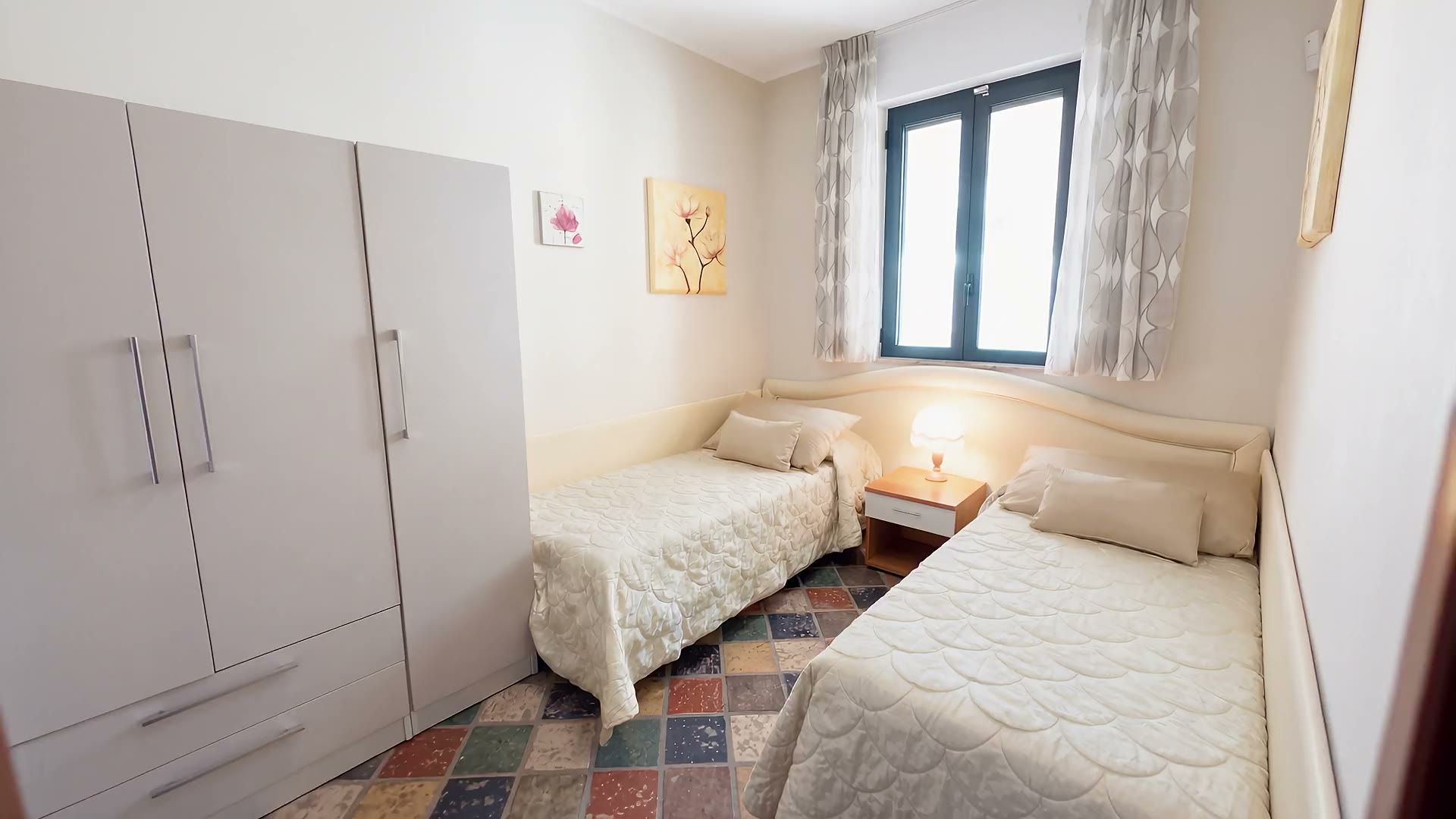 La camera con i due letti singoli di Casa Sabbia d'Oro, la finestra e i quadri con le magnolie