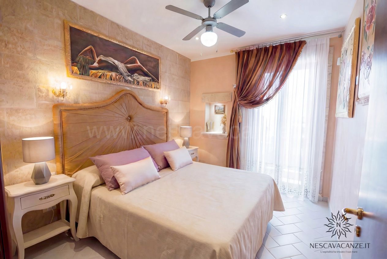 Casa Pescoluse 4 - camera matrimoniale con testiera in legno intagliato, dipinto e comodini bianchi
