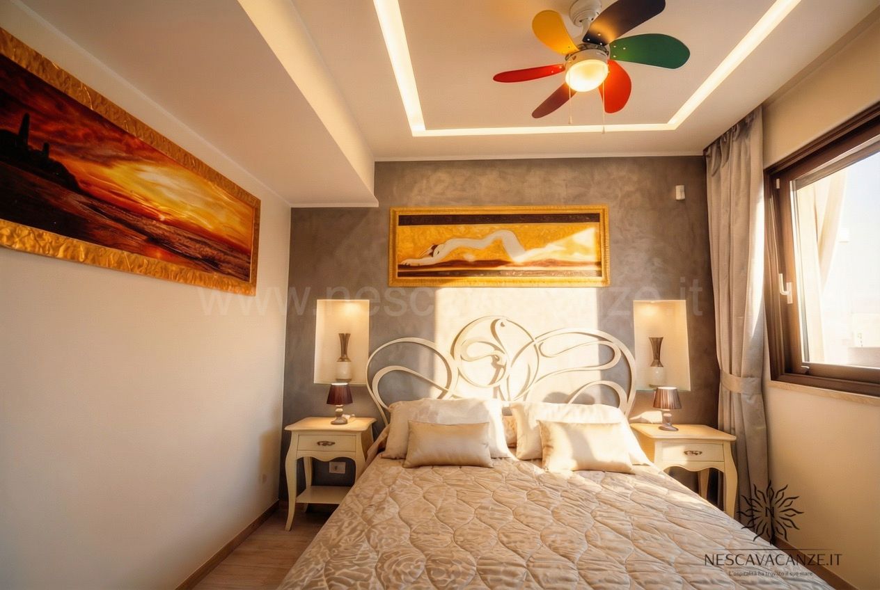 Casa Salento - camera matrimoniale con testiera in ferro battuto, ventilatore colorato e quadri