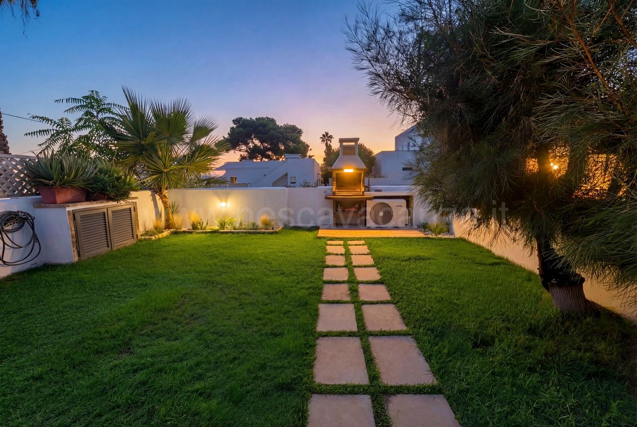 Casa Sabbia Oro - giardino al tramonto con prato, camminamento in pietra e barbecue illuminato
