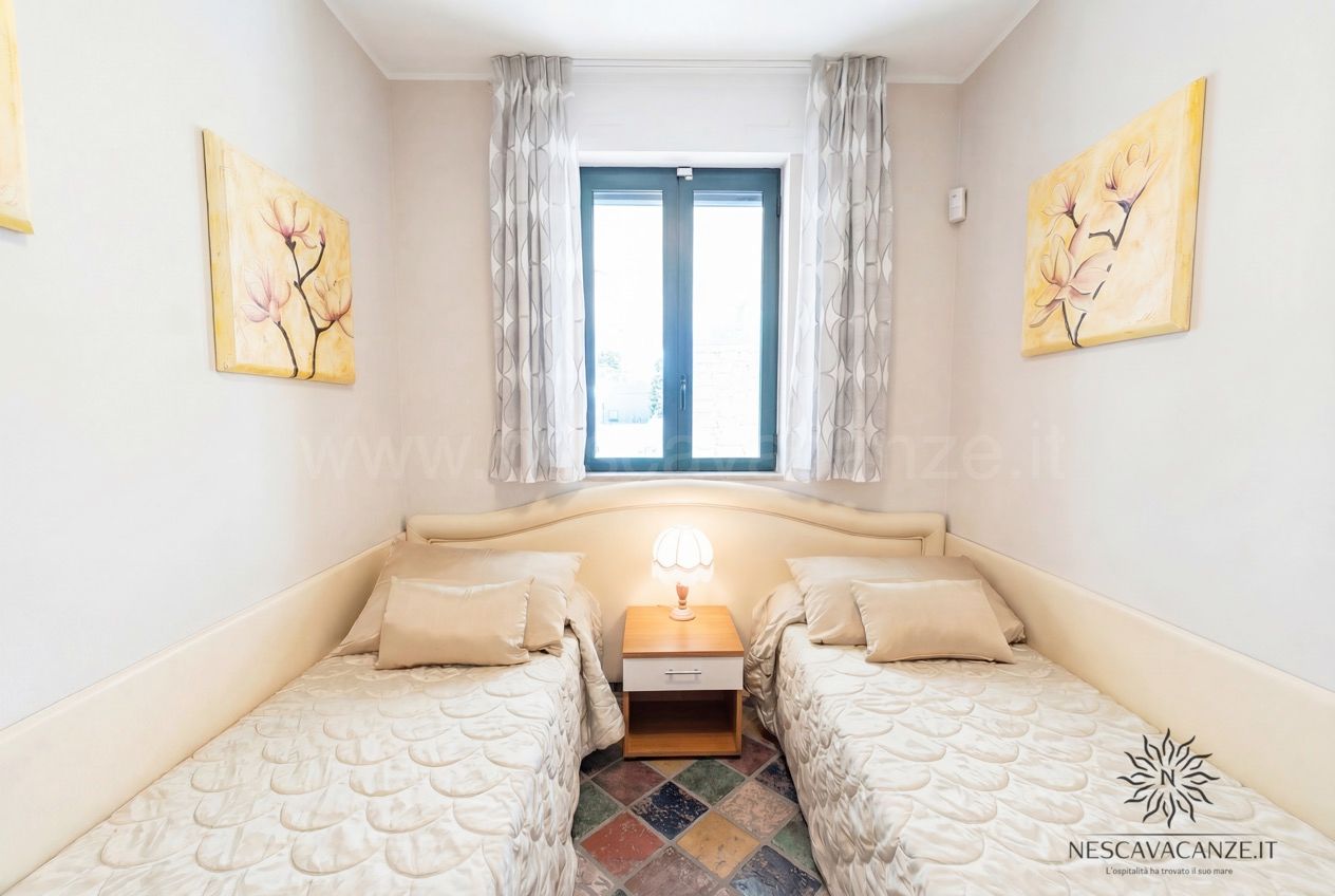 Casa Sabbia Oro - cameretta con due letti singoli, comodino con lampada e quadri gialli a parete