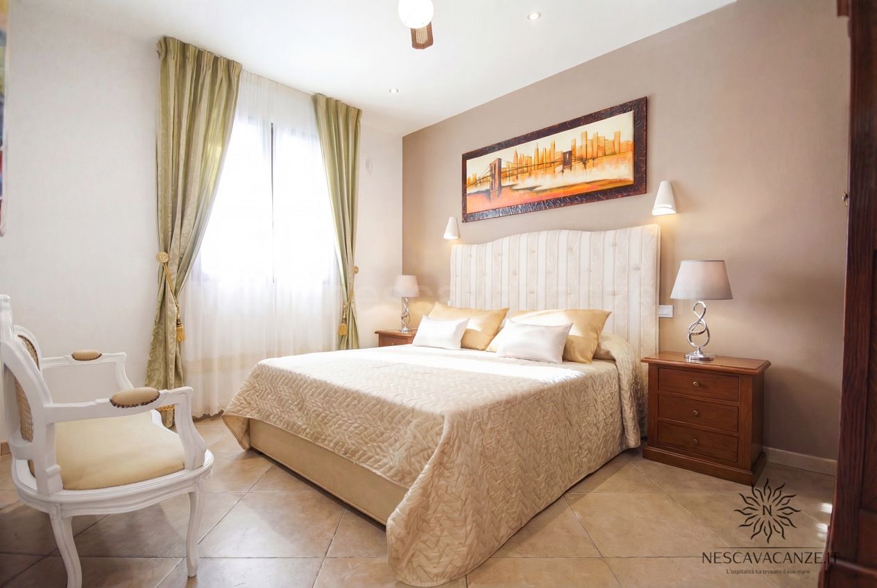 Casa Pescoluse 9 - camera matrimoniale con testiera imbottita, tende verdi e comodini in legno
