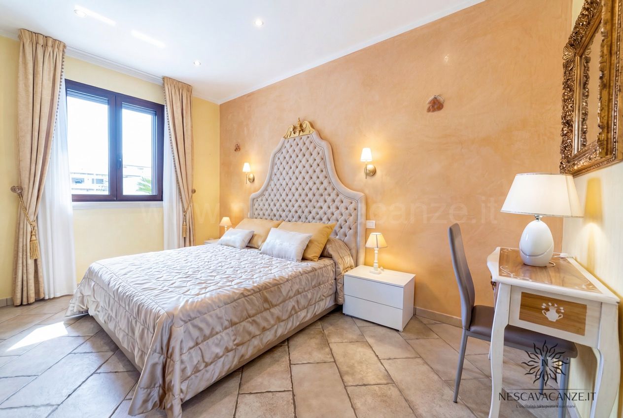 Casa Pescoluse 8 - Camera matrimoniale con testiera capitonné, parete arancio, comodini e scrittoio