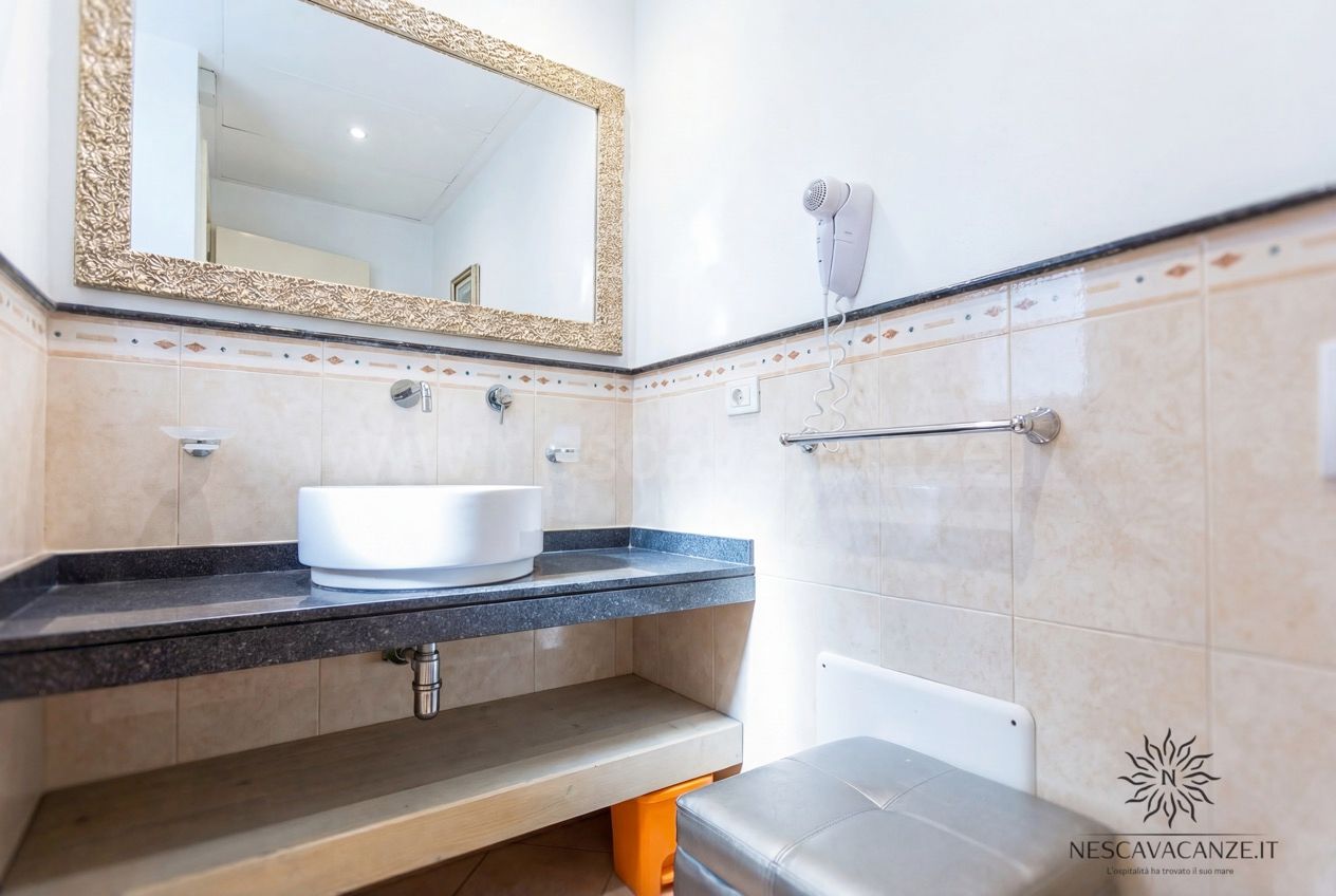 Casa Pescoluse 9 - bagno con lavabo da appoggio, specchio dorato, asciugacapelli e piano scuro