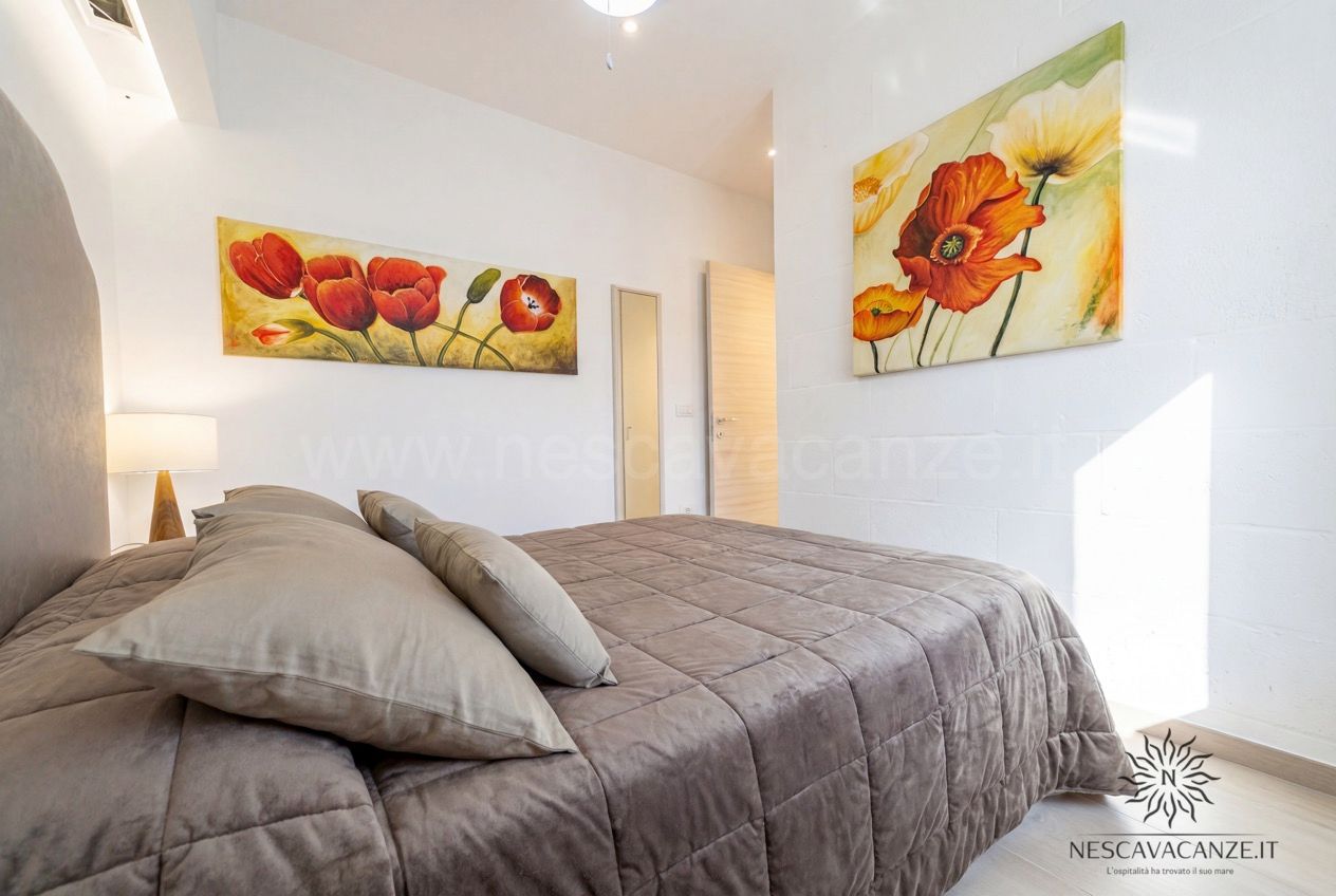Casa Pescoluse 2 - camera matrimoniale con copriletto marrone e quadri di papaveri rossi