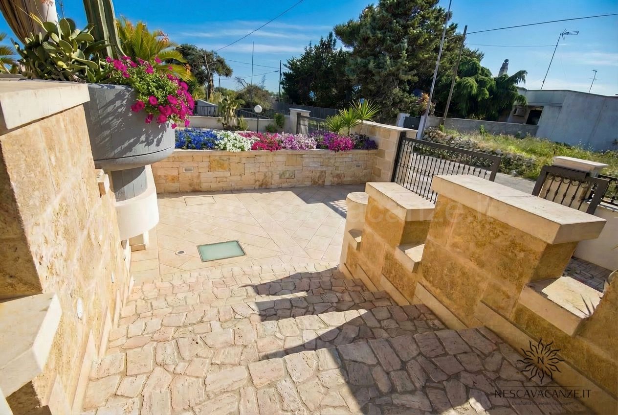 Casa Pescoluse 1 - terrazza pavimentata con muretti in pietra, fioriera fiorita e ringhiera in ferro