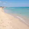 La lunga spiaggia di sabbia di San Pietro in Bevagna con l'acqua chiara