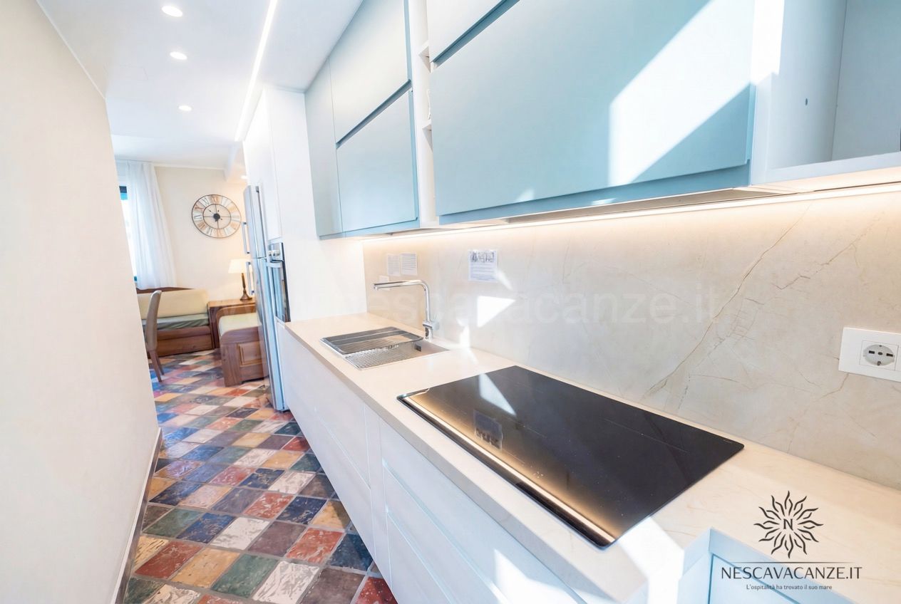 Casa Sabbia Oro - cucina con lavello, piano cottura a induzione, pensili azzurri e schienale in marmo