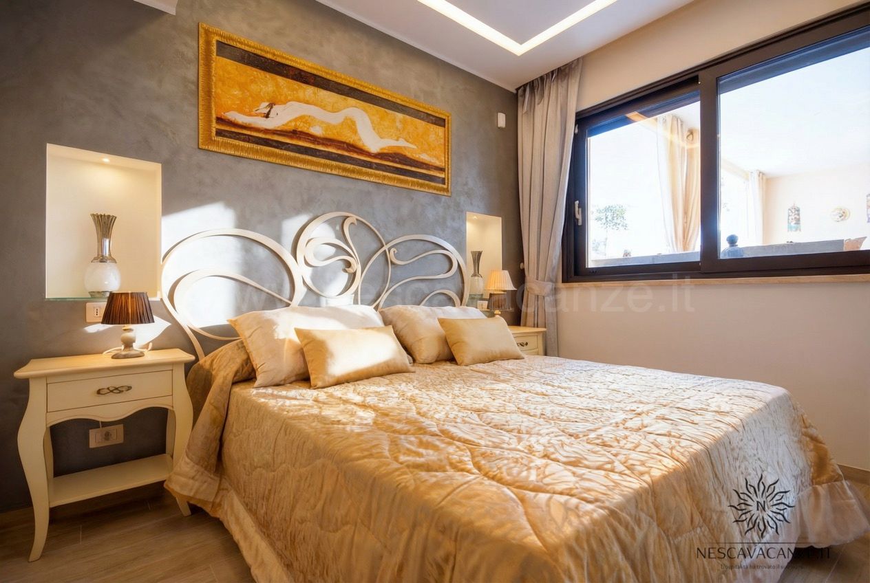 Casa Salento - camera matrimoniale con letto oro, testiera in ferro battuto e finestra sul terrazzo