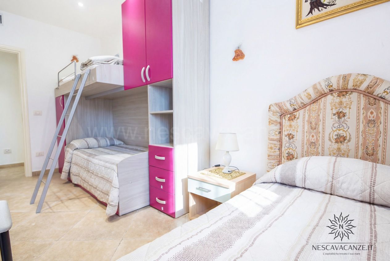 Casa Pescoluse 9 - cameretta con letto a castello fucsia e letto singolo con testiera floreale