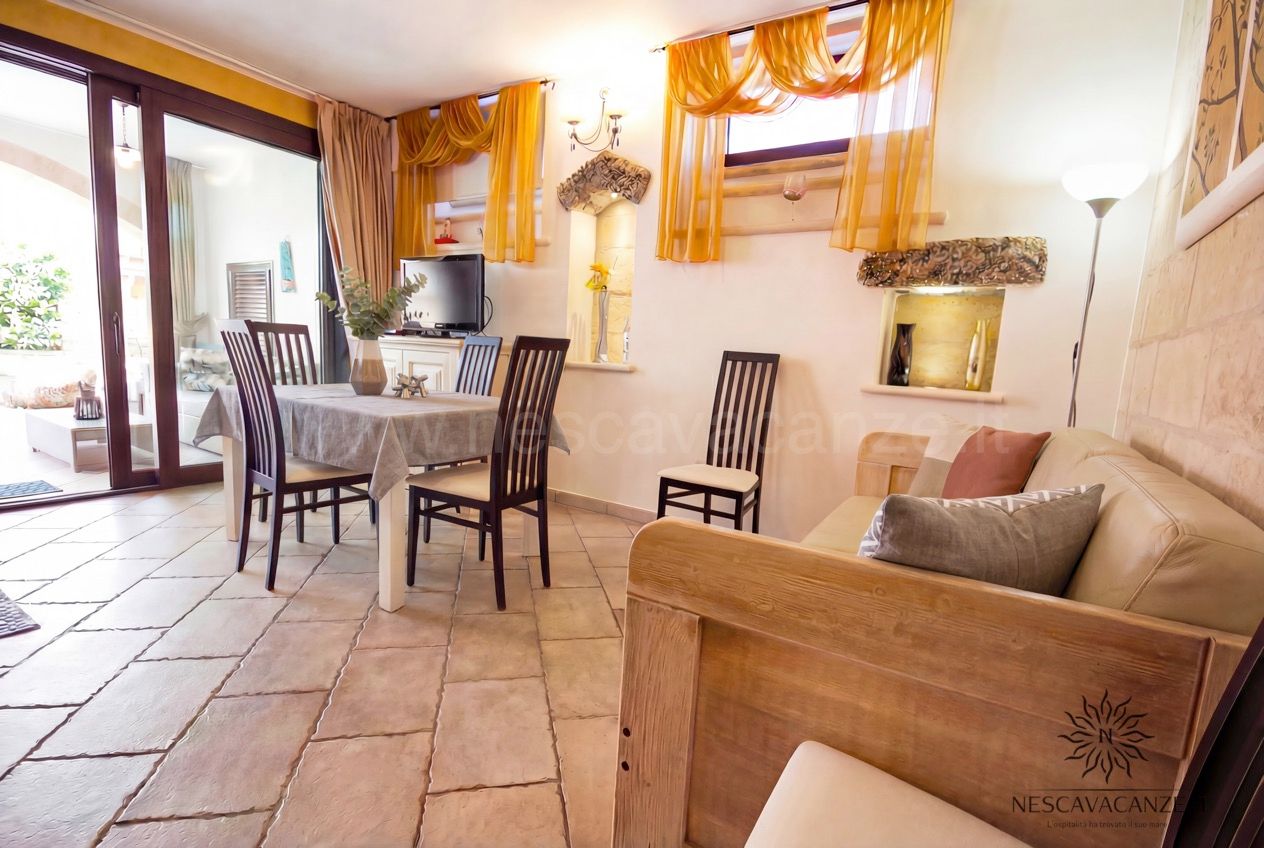 Casa Pescoluse 6 - soggiorno con tavolo da pranzo, sedie, divano in pelle e pavimento in cotto