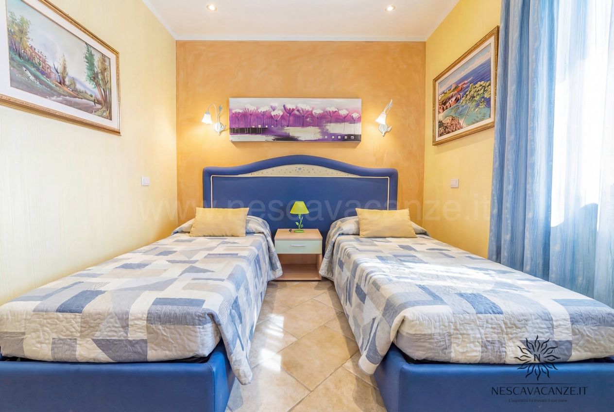 Casa Pescoluse 8 - Camera con due letti singoli, testiere blu, comodino e quadri alle pareti