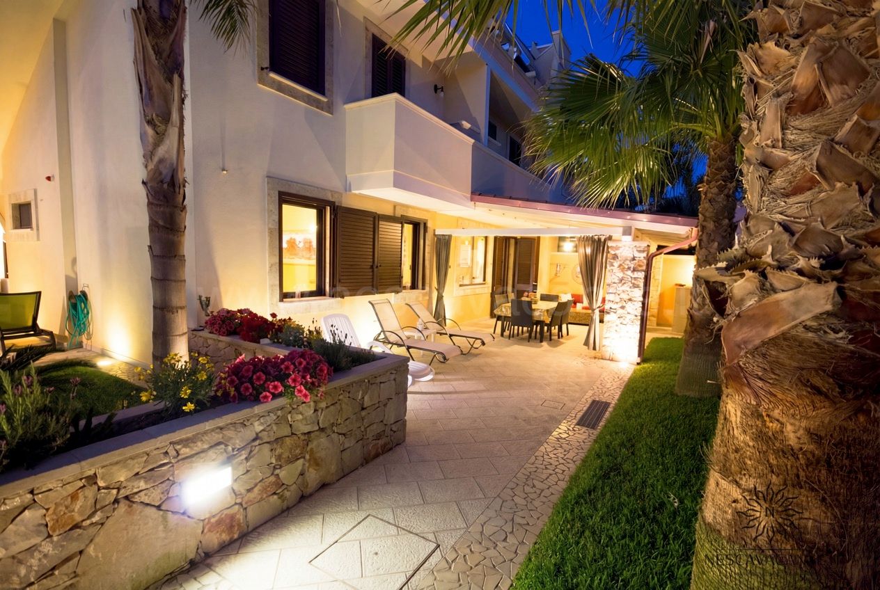 Casa Pescoluse 7 - terrazza laterale illuminata al tramonto con lettini e palme