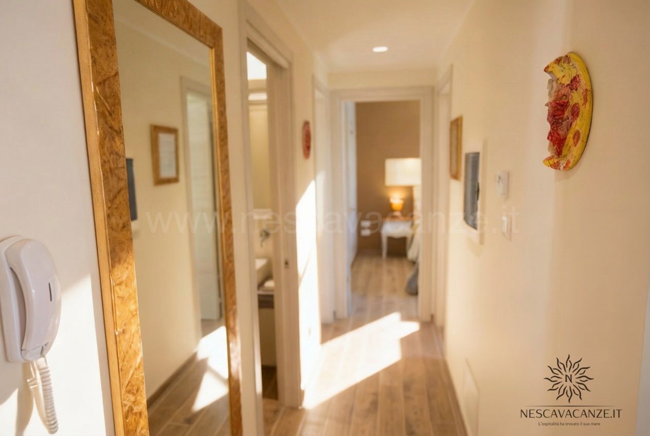 Casa Dune - corridoio interno con pavimento in legno, specchio a figura intera e luce solare che entra dalle finestre