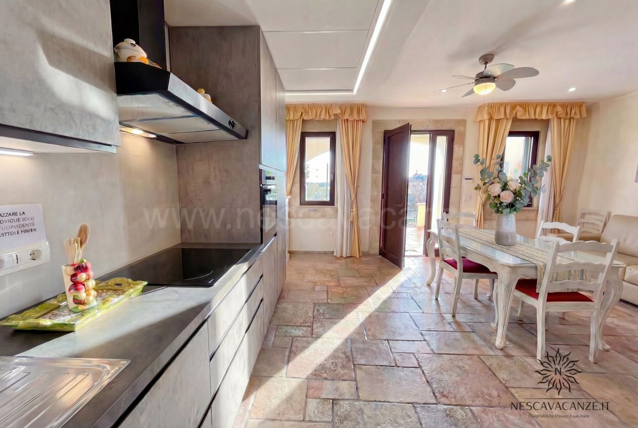 Casa Pescoluse 5 - cucina con piano a induzione, cappa e forno, zona pranzo e tende gialle