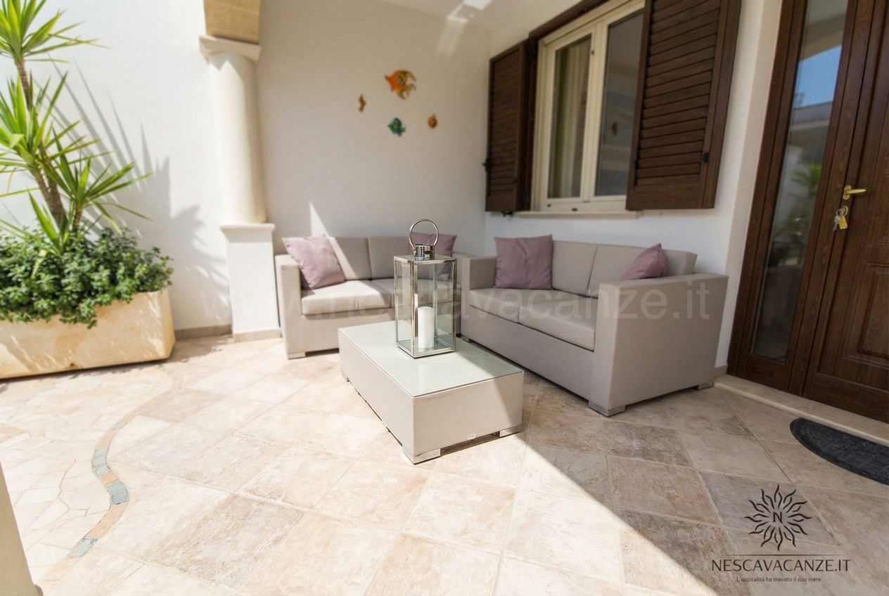 Casa Pescoluse 1 - angolo relax con due divani grigi, tavolino e lanterna su pavimento in pietra