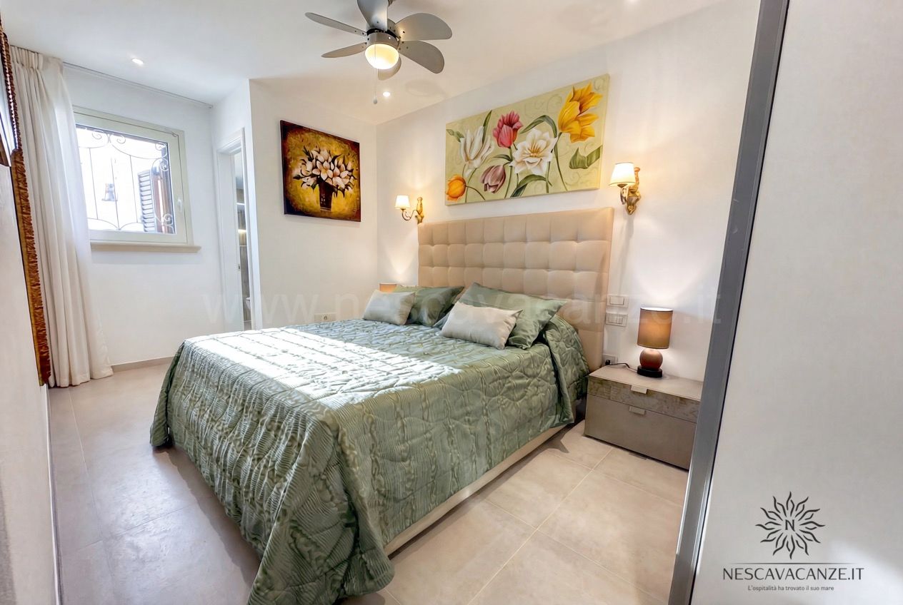 Casa Pescoluse 2 - camera matrimoniale con copriletto verde, quadri floreali e ventilatore