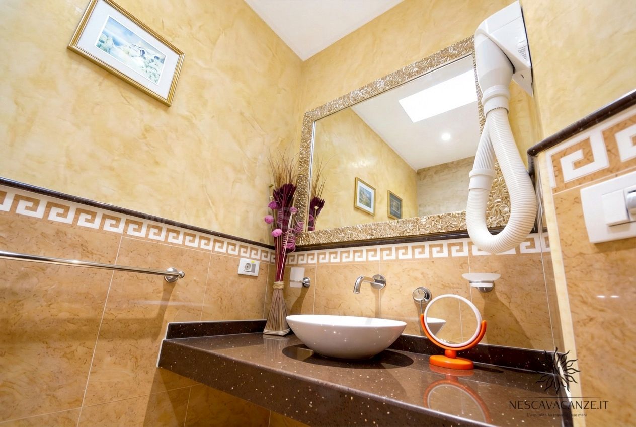 Casa Pescoluse 5 - bagno con lavabo a bacinella, specchio, asciugacapelli e piastrelle beige