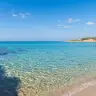 Acqua cristallina sugli scogli e spiaggia ad arco a Marina di Pulsano
