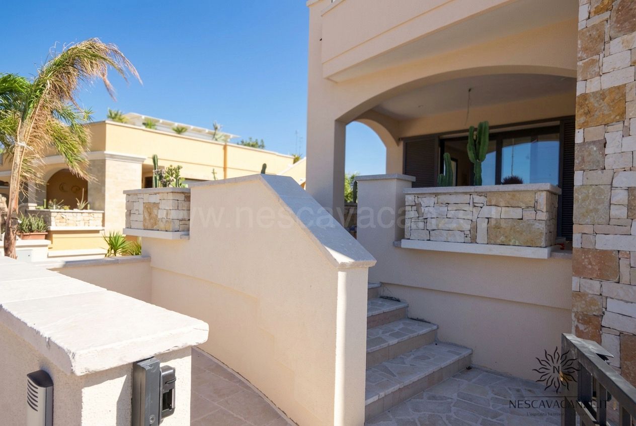 Casa Giglio - ingresso esterno con scala e muretti in pietra sotto cielo azzurro